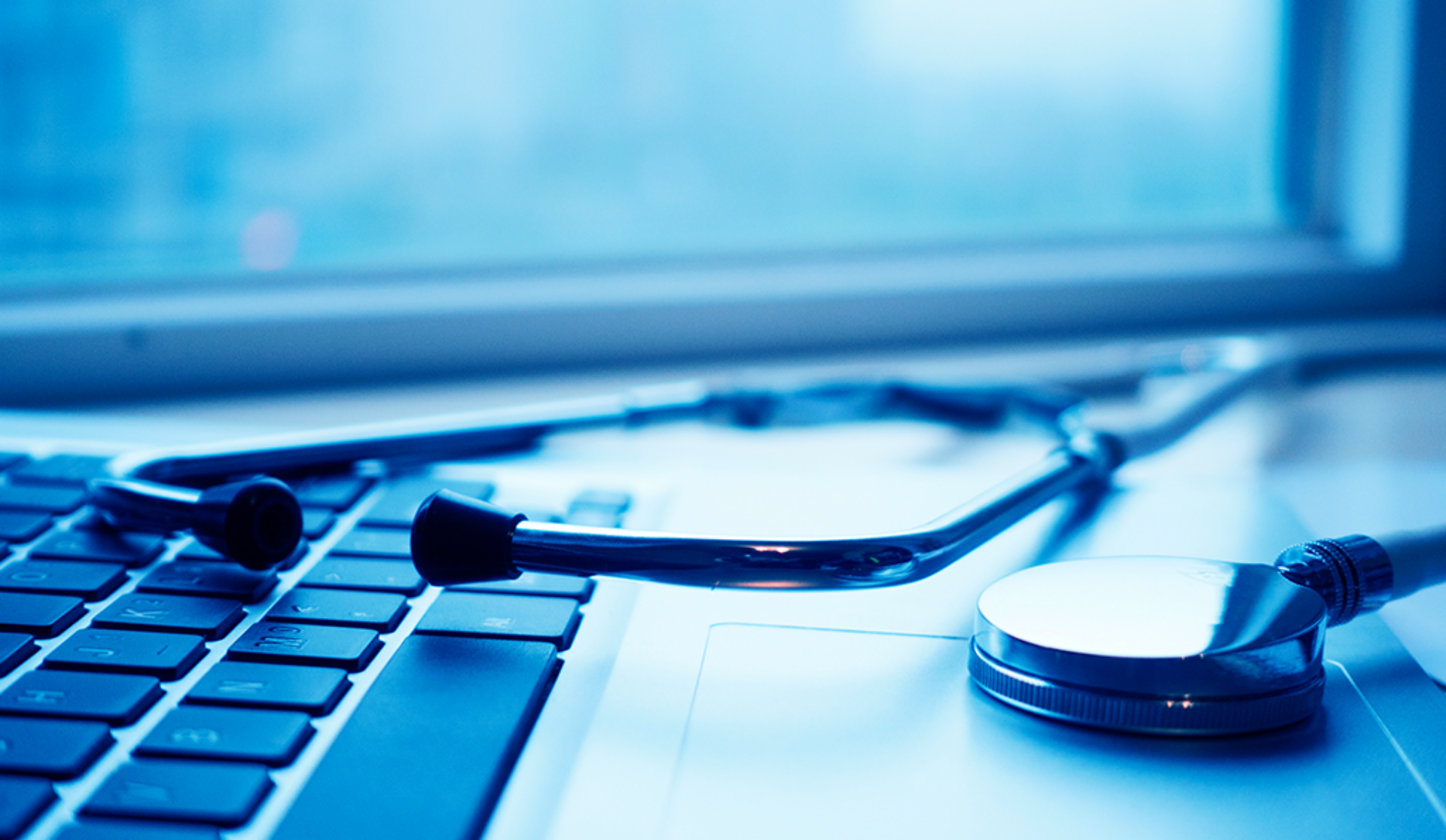 A laptop computer with a stethoscope resting on it, symbolizing the intersection of technology and healthcare.